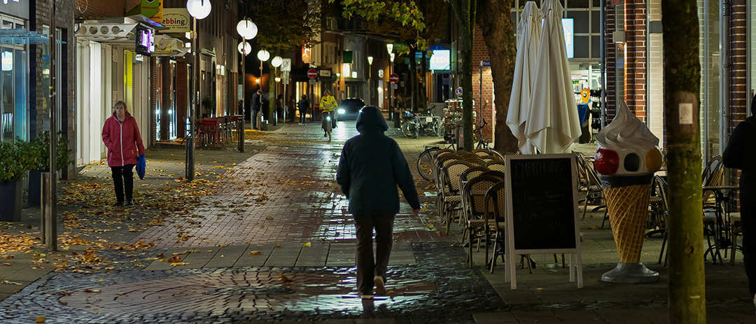 People walking along a quiet neighborhood street in the evening