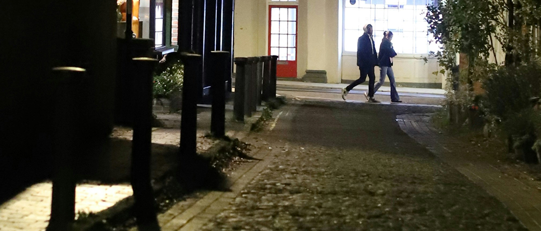 Two people walking together on a quiet city street in the evening