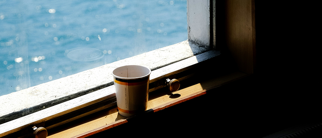 A cup of coffee sitting by a sunlit window in the morning