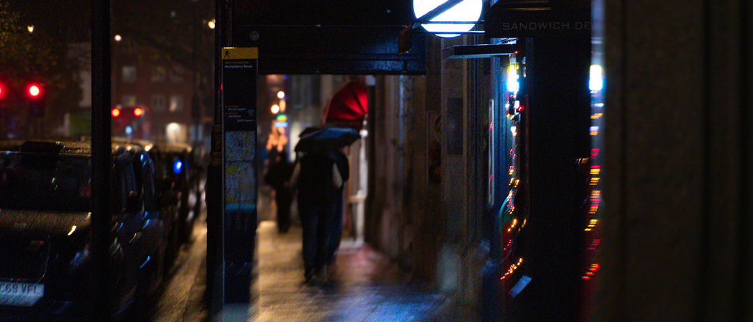 A person walking alone on a rainy city street at night