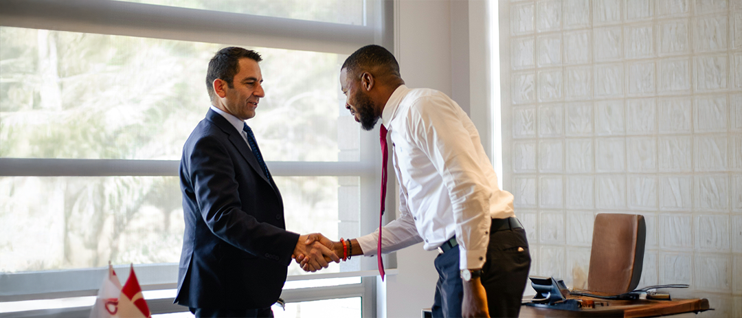 Two business partners shaking hands in an office, representing trust and collaboration