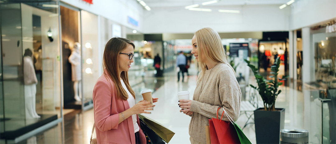 Two people having coffee and conversation at a mall, representing trust and human connection